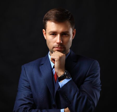 Handsome young business man standing on black backgroundの写真素材