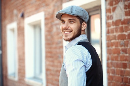 casual young man stands with his back against a brick wallの写真素材