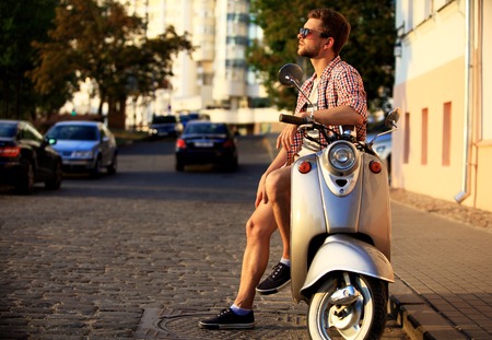 fashionable young man riding a vintage scooter in the streetの素材 [FY31053536744]