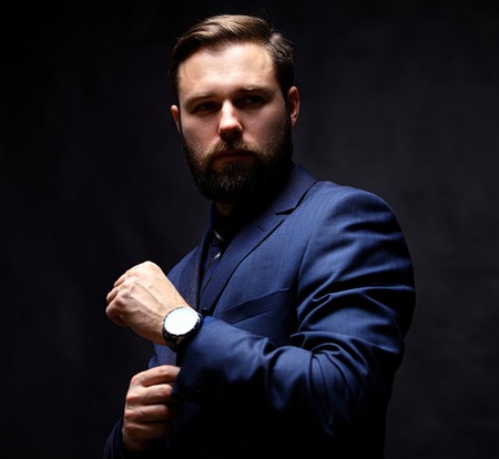 Cool young businessman standing on dark backgroundの写真素材