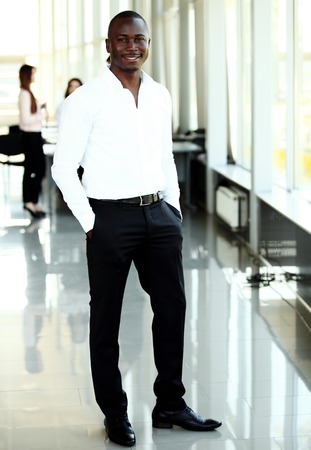 Portrait of smiling African American business man with executives working in backgroundの写真素材