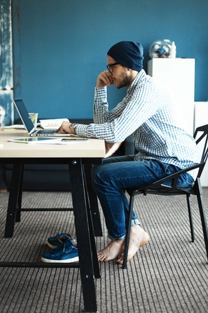 Photo young and talente finance manager working with new project. Handsome man working from his home office. Analyze business plans on laptop. Blurred background, film effectの写真素材