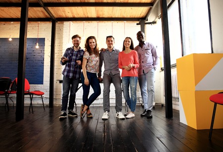 Portrait of happy young people in a meeting looking at camera and smiling. Young designers working together on a creative project.の写真素材