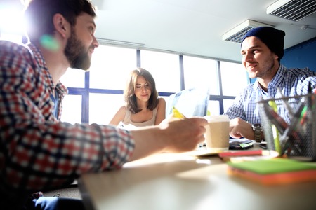Team job. Photo young businessmans crew working with new startup project in modern loft. Generic design notebook on wood table. Horizontal, film effectの写真素材