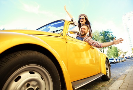 Happy to travel together. Joyful young couple smiling while riding in their convertibleの写真素材