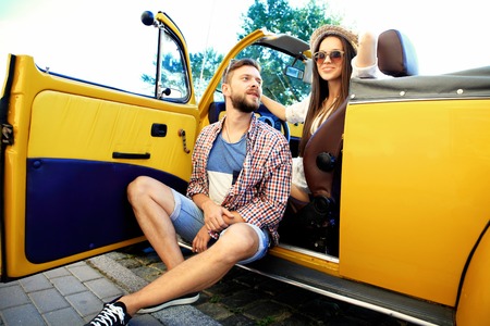 Spending great time together. Beautiful young couple talking and smiling while standing near their new convertibleの写真素材
