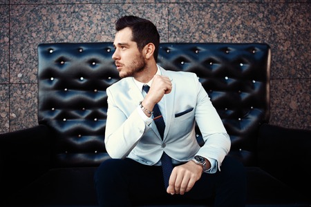 Young handsome bearded stylish man sitting on comfortable leather sofa outdoorsの写真素材