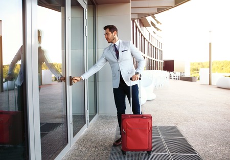 Businessman walking to hotel lobby. Full length portrait of young executive with a suitcase.の写真素材