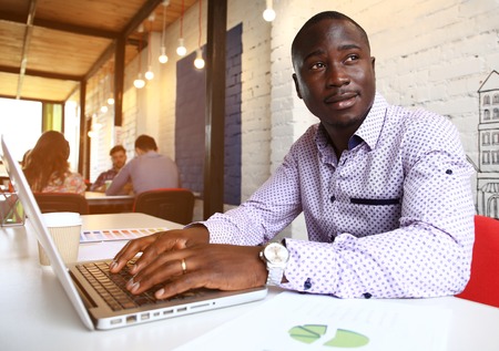 Image of african american businessman working on his laptop. Handsome young man at his desk.の写真素材