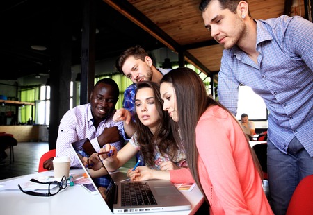 Portrait of happy young people in a meeting looking at camera and smiling. Young designers working together on a creative project.の写真素材