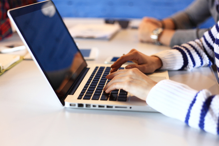 Closeup of a female hands busy typing on laptop. Young professional woman working with computer in officeの写真素材