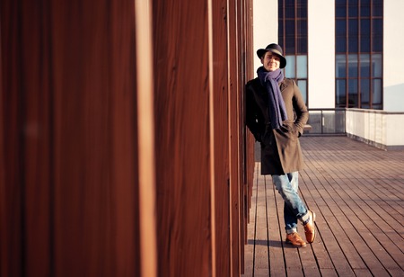Trendy handsome young man in autumn fashion standing in urban environmentの写真素材