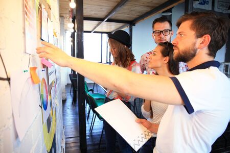 Businessman with young partners looking at whiteboard in creative office.