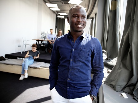 Portrait of happy African guy looking at camera in working environmentの写真素材