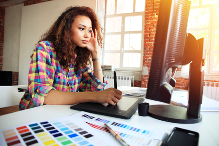 Portrait of a serious businesswoman using laptop in office. Beautiful hipster woman taking notes at modern office.の写真素材