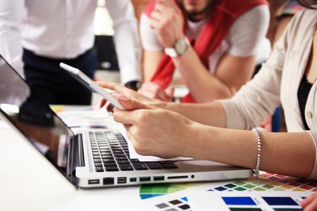 Teamwork,brainstorming concept.Young creative managers team working with new startup project in modern office. Contemporary notebook on wood table.の写真素材