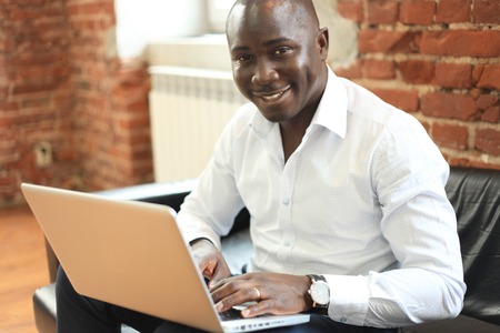 Image of african american businessman working on his laptop. Handsome young man at his deskの写真素材
