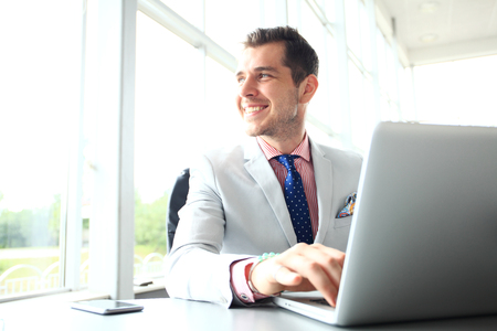 Portrait of young man sitting at his desk in the officeの写真素材