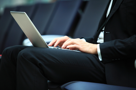 Young adult using laptop in airport loungeの写真素材
