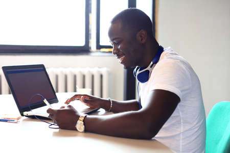 Full concentration. Close-up part of young African man using laptop while sitting at his working...