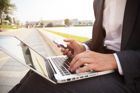 young business man working on a laptop sitting on the streetの写真素材