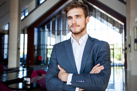 Portrait of happy businessman with arms crossed standing in office.の写真素材