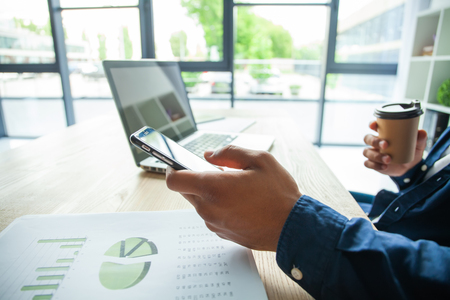 Happy african american businessman using a mobile phone in an office.の写真素材