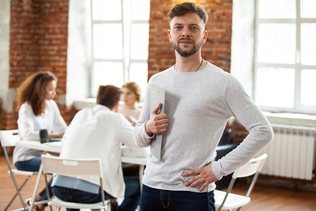 Confident team leader. Confident young man keeping arms crossed and looking at camera with smile...