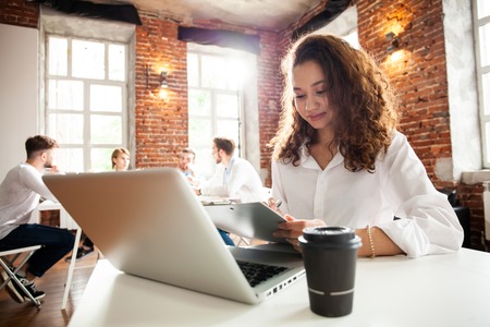 Portrait of cheerful business African-American lady working on laptop.