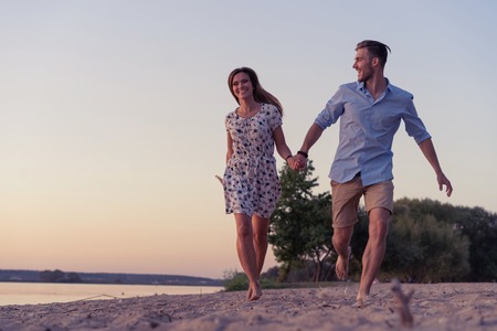 Couple walking on the beach at sunsetの写真素材