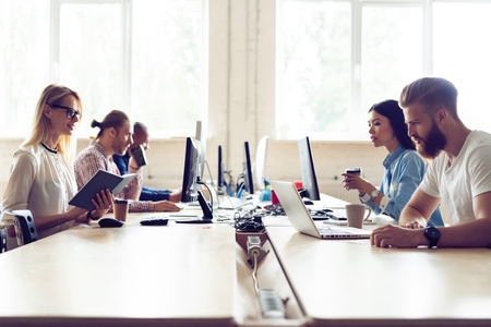 Just working day. Young modern colleagues in smart casual wear working together while spending time in the creative office.の写真素材