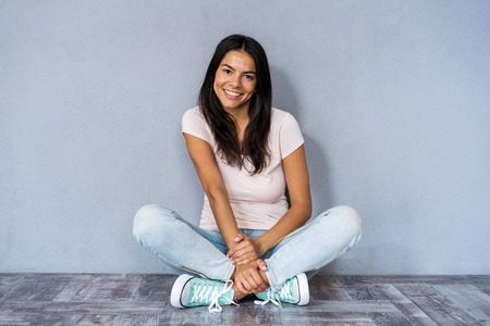 Beautiful smiling young woman sitting on the floorの写真素材