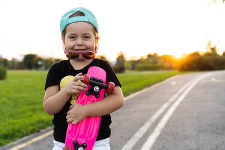 Fashion little girl child with skateboard wearing a sunglasses and hipster shirt.の写真素材