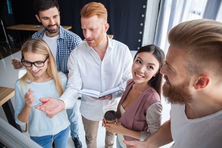 Group of young colleagues dressed casual standing together in modern office and brainstorming.の写真素材