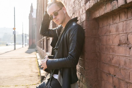 Young man posing with a trendy outfit against a urban background.