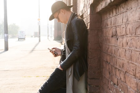 Young man posing with a trendy outfit against a urban background.の写真素材