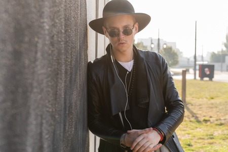 Young man posing with a trendy outfit against a urban background.の写真素材