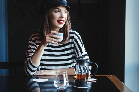 pretty young woman sitting in the cafe with a cup of tea.