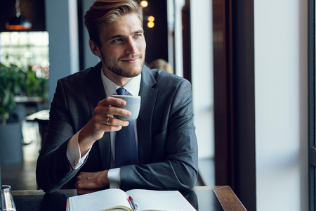 Business man drinking coffee in a cafeの写真素材