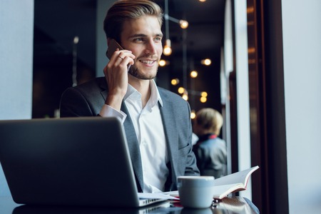 Handsome businessman talking on the phone during coffee break in a cafe.の写真素材
