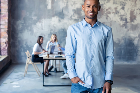 Portrait of smiling African American business man with executives working in background.の写真素材