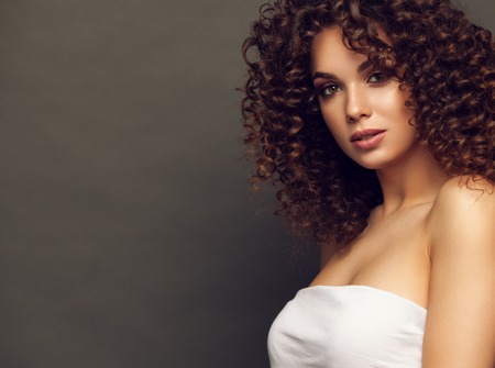 Fashion studio portrait of beautiful smiling woman with afro curls hairstyle. Fashion and beauty.の写真素材