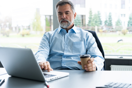Senior businessman working on laptop computer in the office.