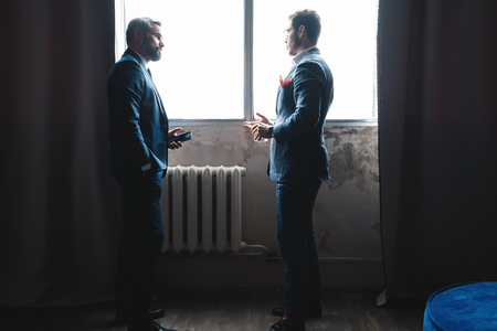 Developing new project. Two modern men in formalwear working together while standing indoors.の写真素材