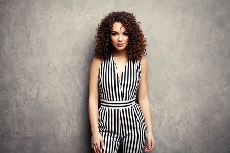 Fashion Model girl isolated over gray background. Beauty stylish brunette woman posing in fashionable clothes in studio. Casual style with beauty accessories. High fashion urban styleの写真素材