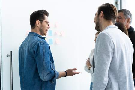 business, education and office concept - business team with flip board in office discussing something.の写真素材