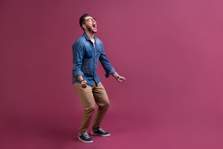 Portrait of a satisfied young man celebrating success isolated over pink background.の写真素材