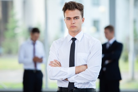 Smiling Businessman posing while colleagues talking together in office.の写真素材