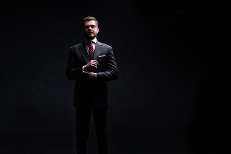 Full length portrait of a fashion male model over black background. Looking at camera.の写真素材