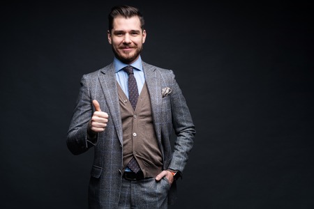 Portrait of excited satisfied cheerful confident positive handsome demonstrating thumbs-up pointing up isolated on black background.の写真素材